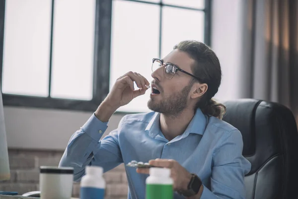 Homme barbu à lunettes prenant une pilule — Photo