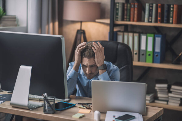 Young bearded man in eyeglasses feeling desperate