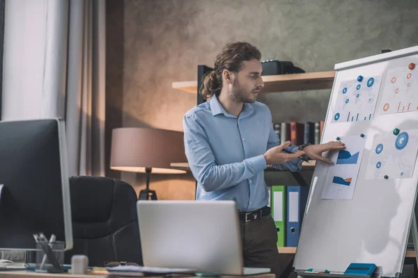 Young bearded man in eyeglasses looking busy at the white board — ストック写真