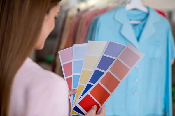 Σχεδιαστής κορίτσι εξετάζει συνδυασμό χρωμάτων με κλίμακες χρωμάτων στα χέρια. — Φωτογραφία Αρχείου