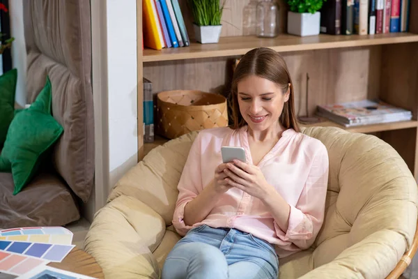 Junge und schöne Frau, die mit ihrem Smartphone SMS schreibt — Stockfoto