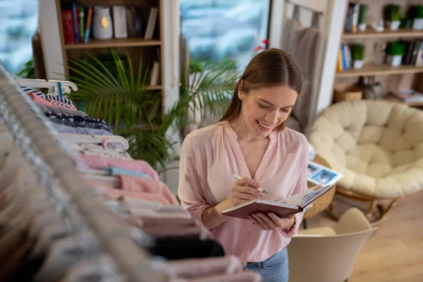 Fiatal stylist teszi ötleteit a noteszébe — Stock Fotó