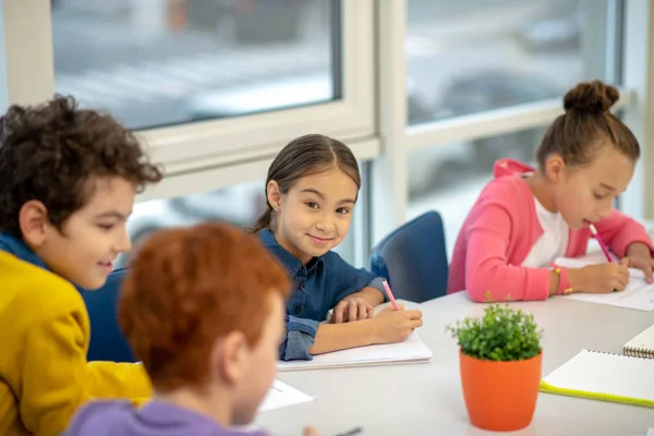 Cheerful girl looking at her classmates during the test — Stock Photo, Image
