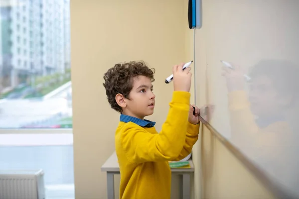 Jongen die op het whiteboard schrijft met stift — Stockfoto