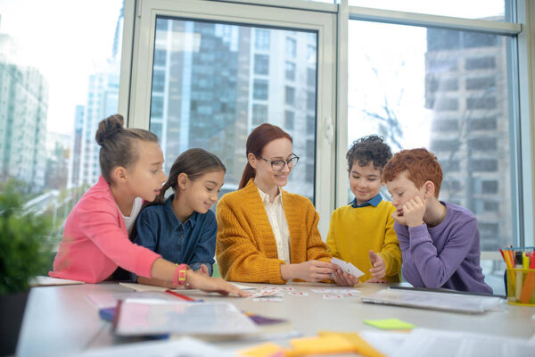 Cheerful teacher showing words game to pupils