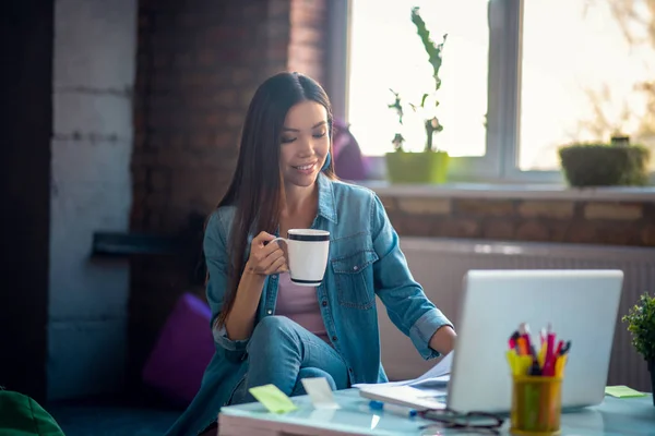 Angenehm gut aussehende Frau sitzt mit einer Teetasse — Stockfoto