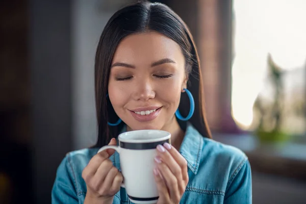 Щаслива гарна молода жінка пахне кавою — стокове фото