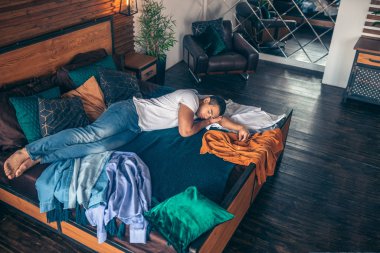 Dark-haired young man in white tshirt having a nap