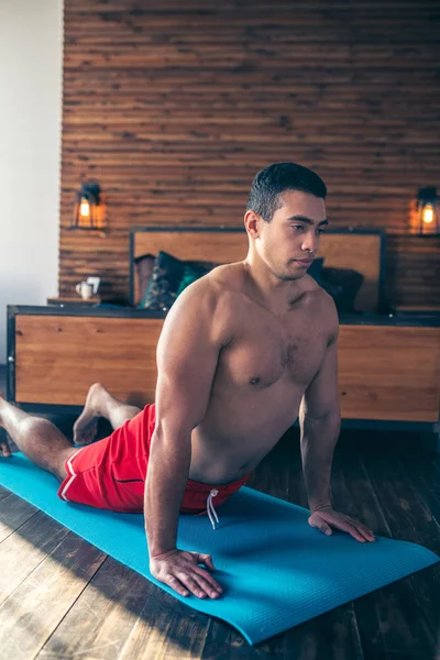 Hombre guapo de pelo oscuro en pantalones cortos rojos haciendo ejercicio — Foto de Stock