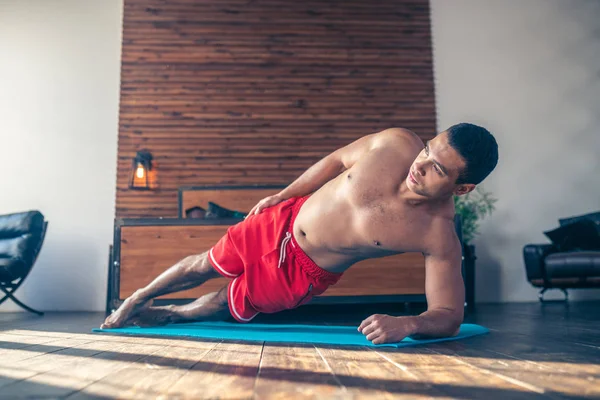 Knappe man in rood shorts staan in de zij plank — Stockfoto