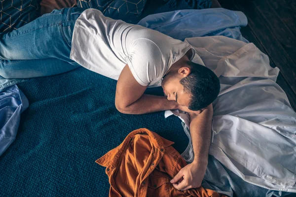 Joven moreno en camiseta blanca durmiendo en la cama — Foto de Stock