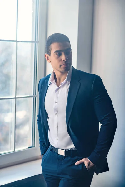 Dark-haired young man in elegant suit standing near the window — 스톡 사진