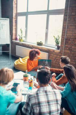 Öğrenci, projesini arkadaşlarına sunarken dizüstü bilgisayarını tutuyor