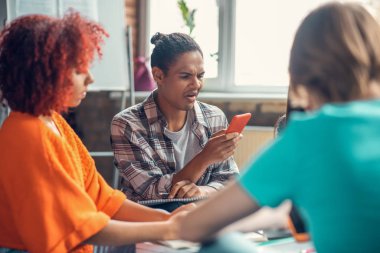 Öğrenci elinde telefonla arkadaşlarıyla konuşurken komik bir ifade takınıyor.