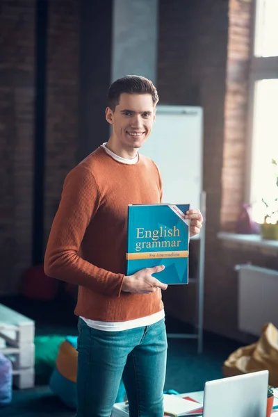 Student wearing jeans and sweater holding English book — Stock Photo, Image