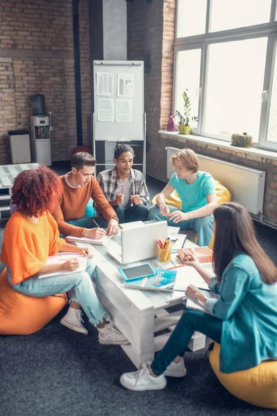 Estudiantes sentados a la mesa y preparándose para la presentación en grupo — Foto de Stock