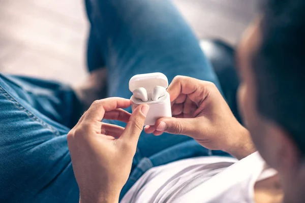 Kabellose weiße Kopfhörer in den Händen eines Mannes. — Stockfoto