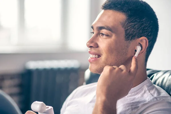 Guapo escuchando música a través de auriculares inalámbricos . — Foto de Stock
