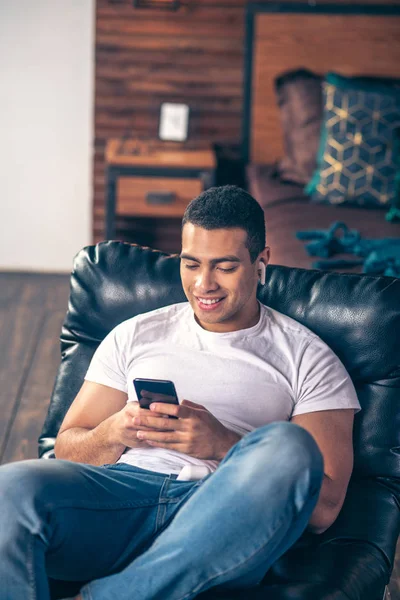 Guapo chico descansando en una silla con gadgets . — Foto de Stock