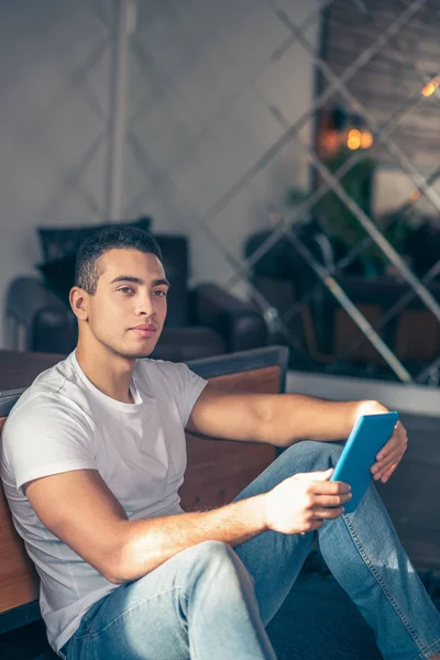 Tipo guapo sentado en el suelo pensando con una tableta . — Foto de Stock