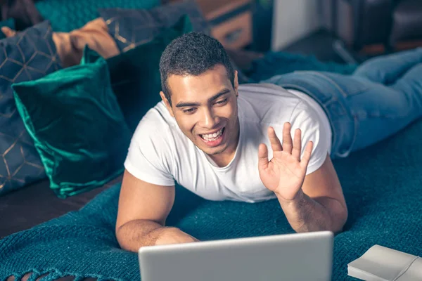 Joven sonriente se comunica en línea en un ordenador portátil . —  Fotos de Stock