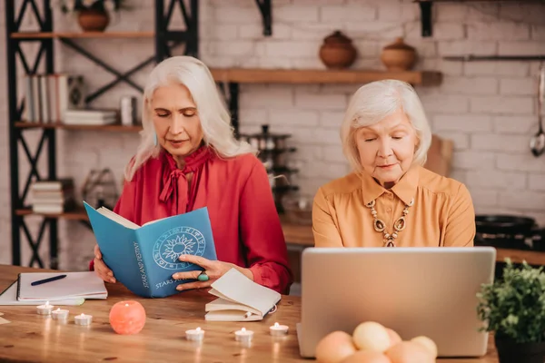 Dos señoras de pelo gris agradables que parecen involucradas mientras estudian juntas — Foto de Stock