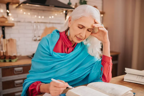 Седовласая красивая пожилая леди в синей шале читает книгу — стоковое фото