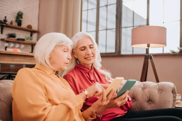 Dos mujeres ancianas de pelo gris de aspecto agradable discutiendo fotos en línea — Foto de Stock