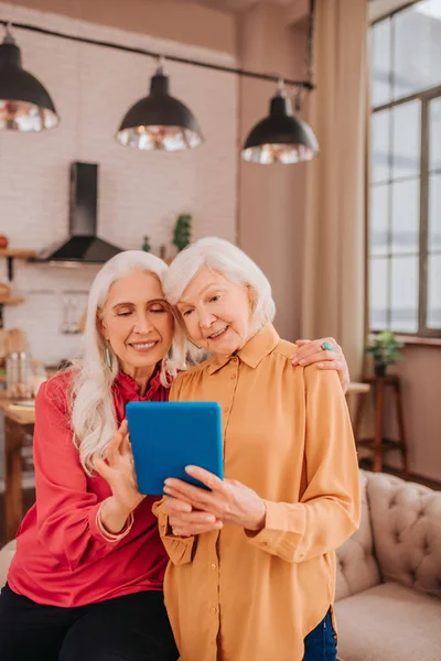 Two pleasant-looking elderly grey-haired women standing in the room — Stock Photo, Image