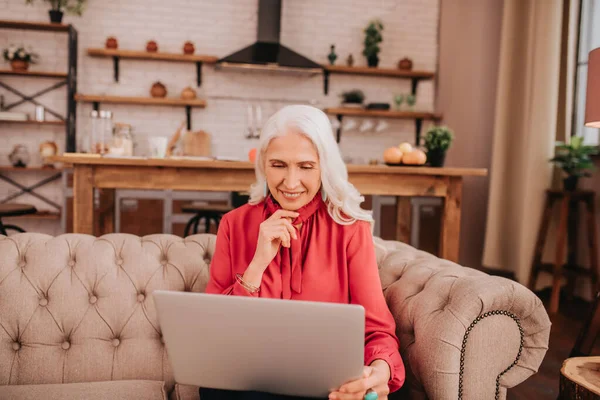 Long-haired beautiful lady in red having a video call — Stock Photo, Image