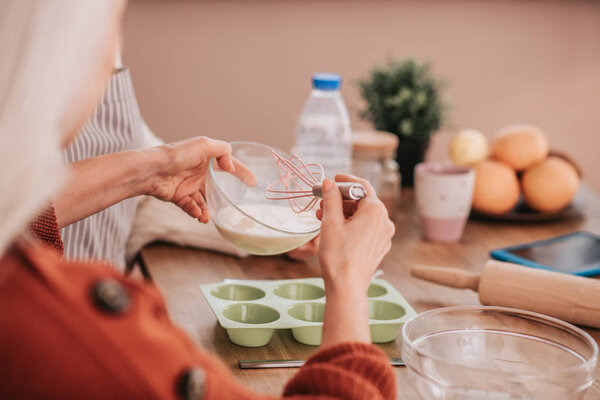 Close up of womans hands holding a whisk for whipping