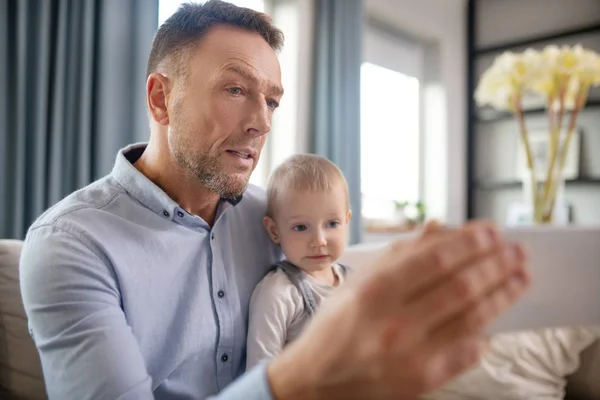 Зрелый отец показывает что-то своему ребенку на планшете — стоковое фото