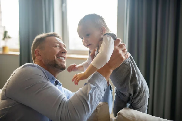 Homem barbudo sorrindo enquanto segurava sua filha bebê — Fotografia de Stock