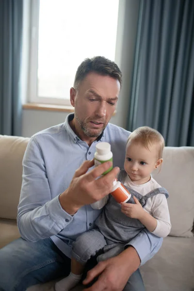 Отец держит своего ребенка и выбирает таблетки — стоковое фото
