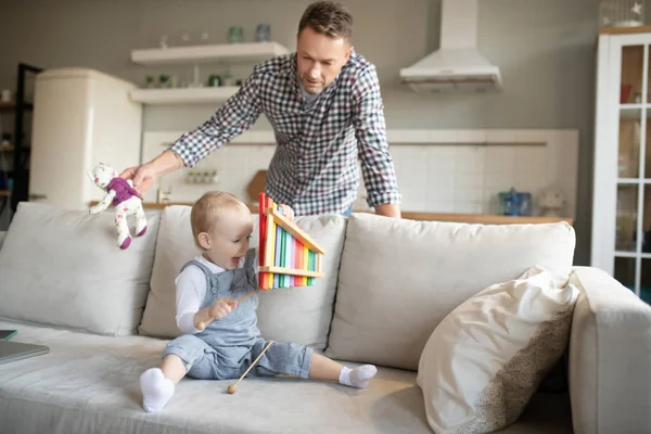 Padre con una camisa a cuadros mirando a su hijo jugueteando —  Fotos de Stock