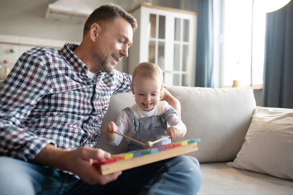 Père en chemise à carreaux regardant sa fille jouer du xylophone — Photo