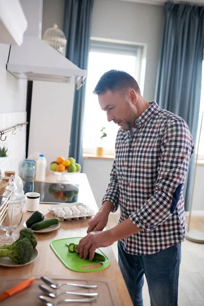 Man in een geblokt hemd die groenten snijdt — Stockfoto