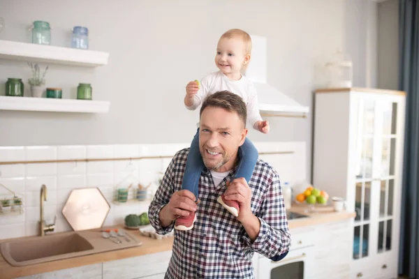 Padre con camisa a cuadros sosteniendo a su hijita sobre sus hombros —  Fotos de Stock