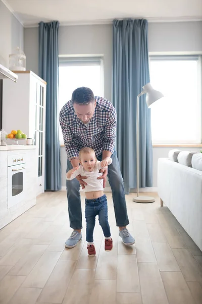 Otec v kostkované košili pomáhá své malé dceři chodit — Stock fotografie