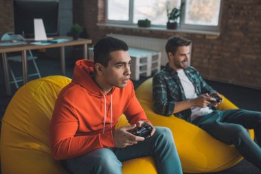 Oyun konsoluyla oturan yakışıklı bir adam.