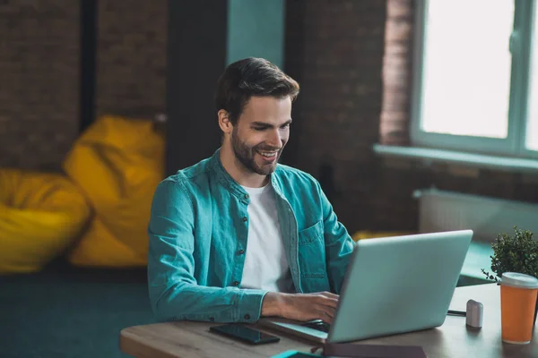 Boldog jóképű férfi dolgozik a laptopján. — Stock Fotó