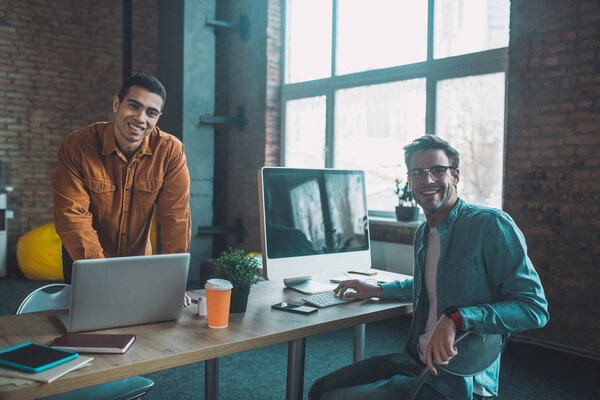 Happy positive men being in a good mood at work