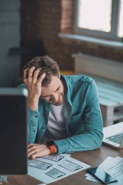 Depresyondaki genç adam elini başına koyuyor.