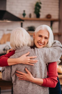 Two mature grey-haired positive ladies enjoying together