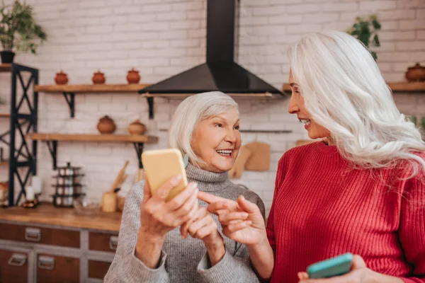 Dos señoras maduras de pelo gris positivas hablando de nuevas tecnologías — Foto de Stock