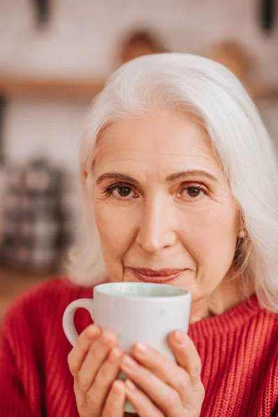 Hermosa anciana en blusa roja disfrutando de su té — Foto de Stock