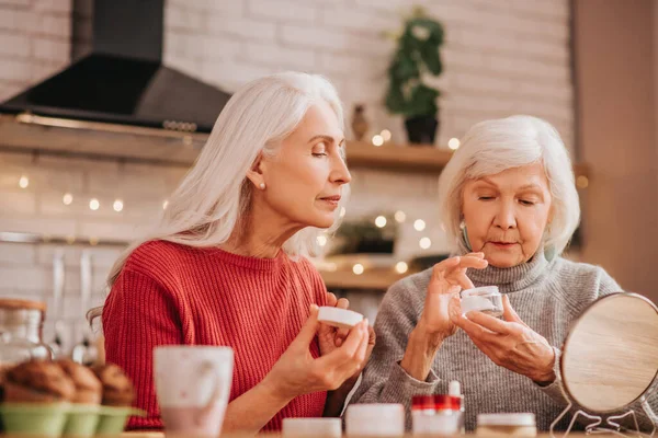 Dos ancianas guapas aplicando crema nueva — Foto de Stock