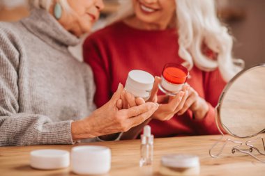 Two good-looking elderly women talking about skin care