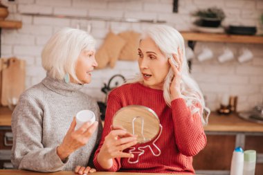 Two good-looking elderly women talking in the kitchen