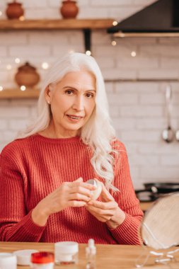 Grey-haired beautiful lady in red blouse looking contented